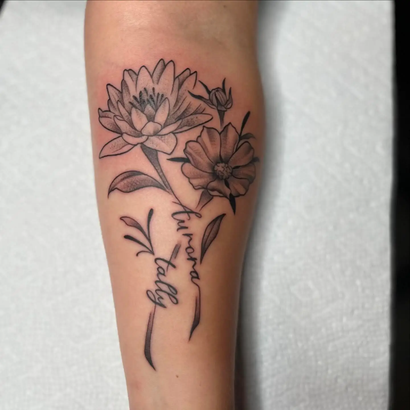 Birth flower stems with script on a forearm