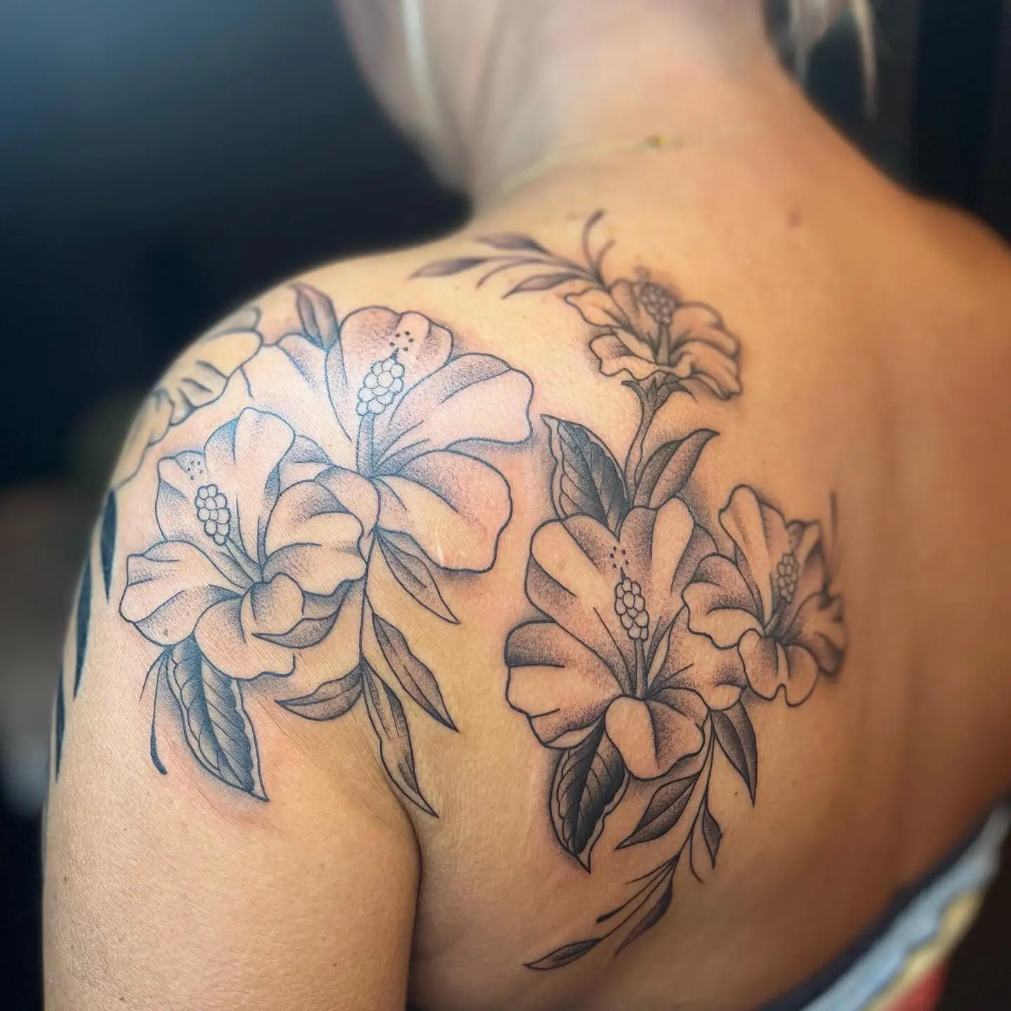 Black and grey hibiscus flowers wrapping a shoulder