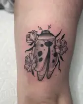 Stipple shaded ladybug tattoo surrounded by small flowers