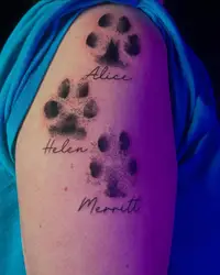 Three dog paw prints with names on an upper arm