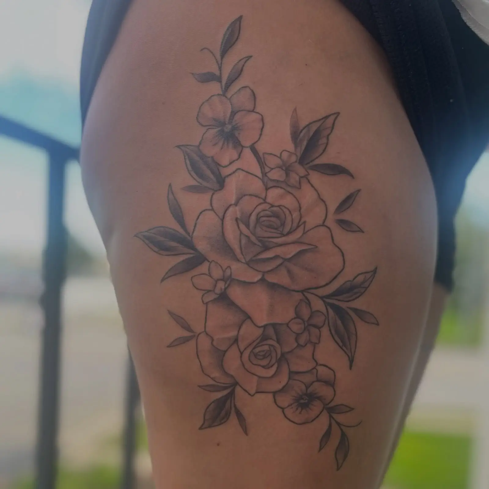Stacked black and grey roses on the side of a thigh