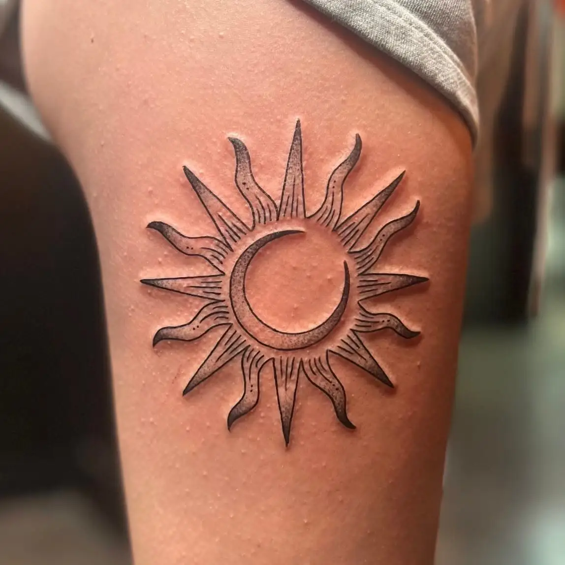 Sun with a crescent moon face in black and grey