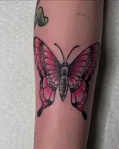 Bold traditional butterfly in pink and black on a forearm