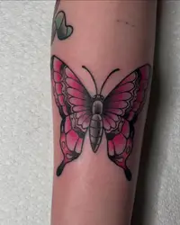 Bold traditional butterfly in pink and black on a forearm
