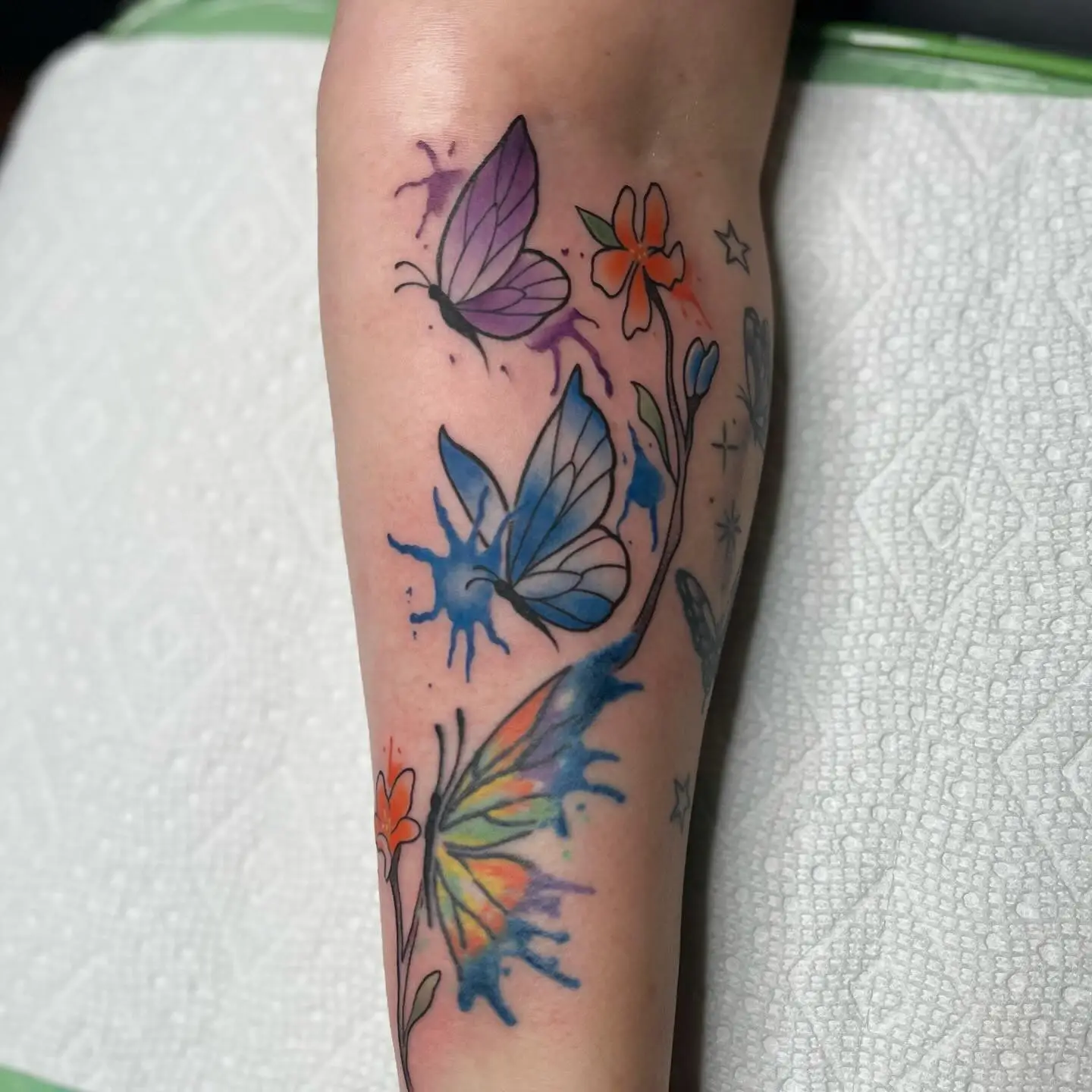Butterflies and flowers with watercolor shading on a forearm